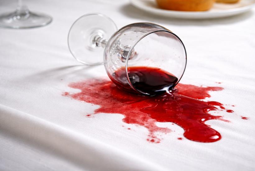 Опрокинутый бокал вина на белой скатерти