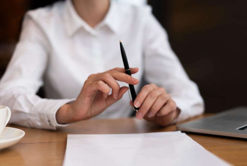 Женщина в белой блузке подписывает документы