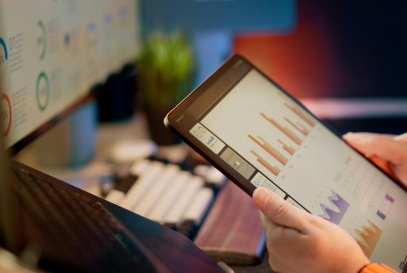 Рука указывает на растущий финансовый график на планшете