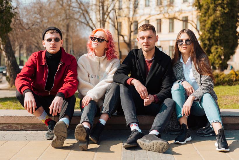 Друзья сидят на бордюре на улице