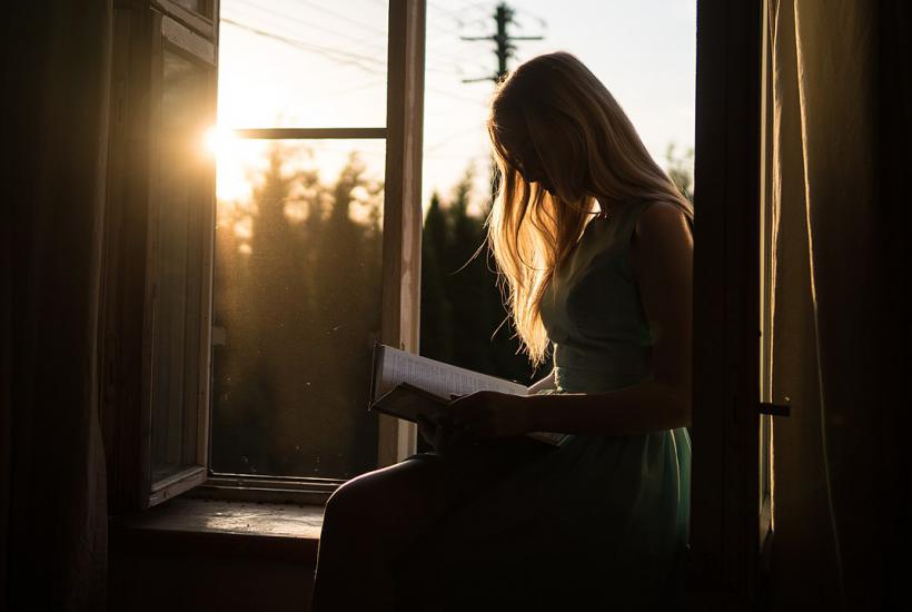 Девушка читает книгу в полумраке