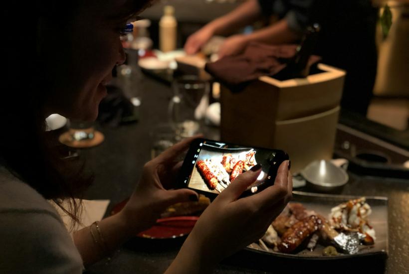 Девушка фотографирует еду на смартфон в ресторане