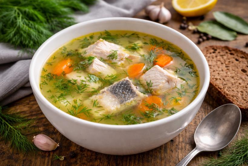 Тарелка ухи с зеленью и хлебом