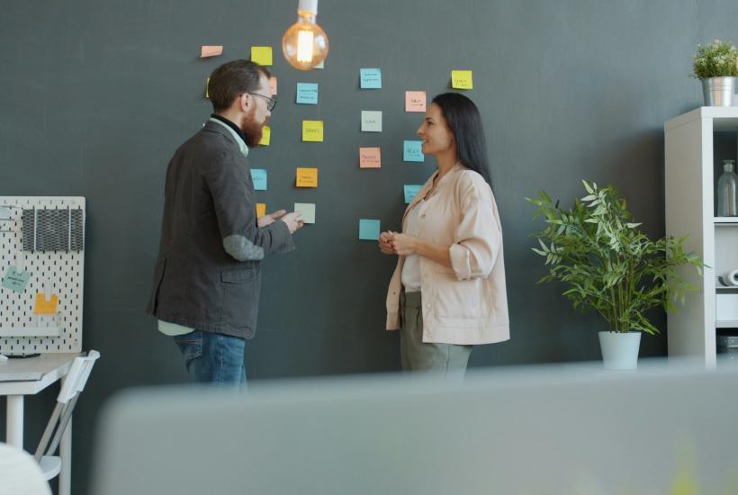 Сотрудники проводят мозговой штурм у белой доски со стикерами