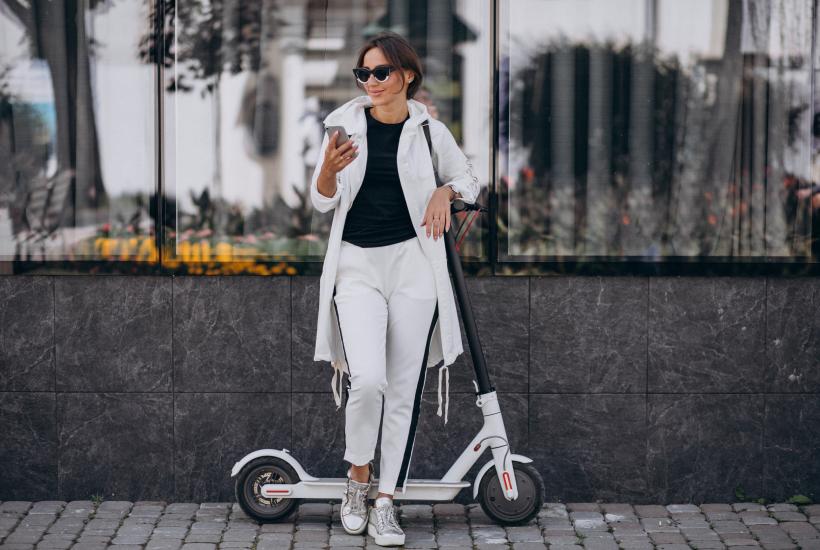 Красивая женщина в белом с самокатом