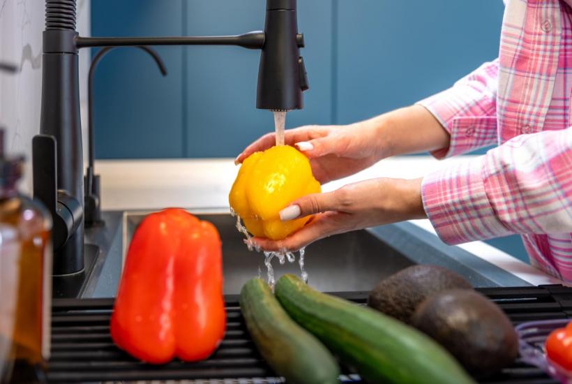 Девушка моет овощи