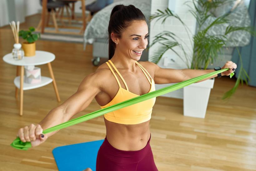 Женщина тренируется дома с лентой